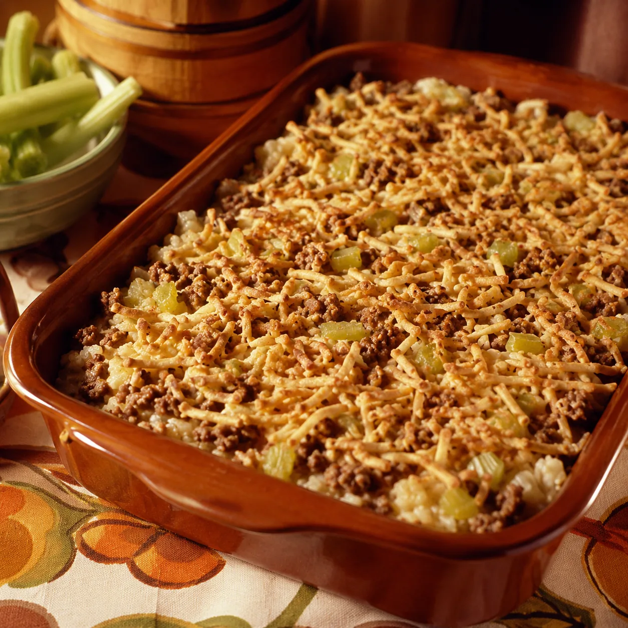 Realistic editorial photo of chop suey casserole with rice, celery, ground beef, and crunchy noodles in a baking dish, p