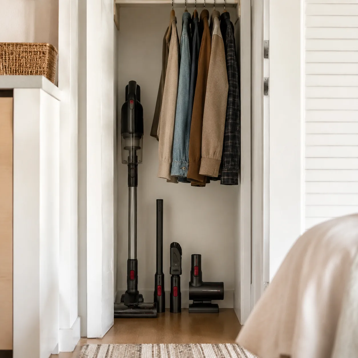Realistic editorial photo of vacuum attachments arranged near a compact cordless vacuum in a smaller apartment closet, p