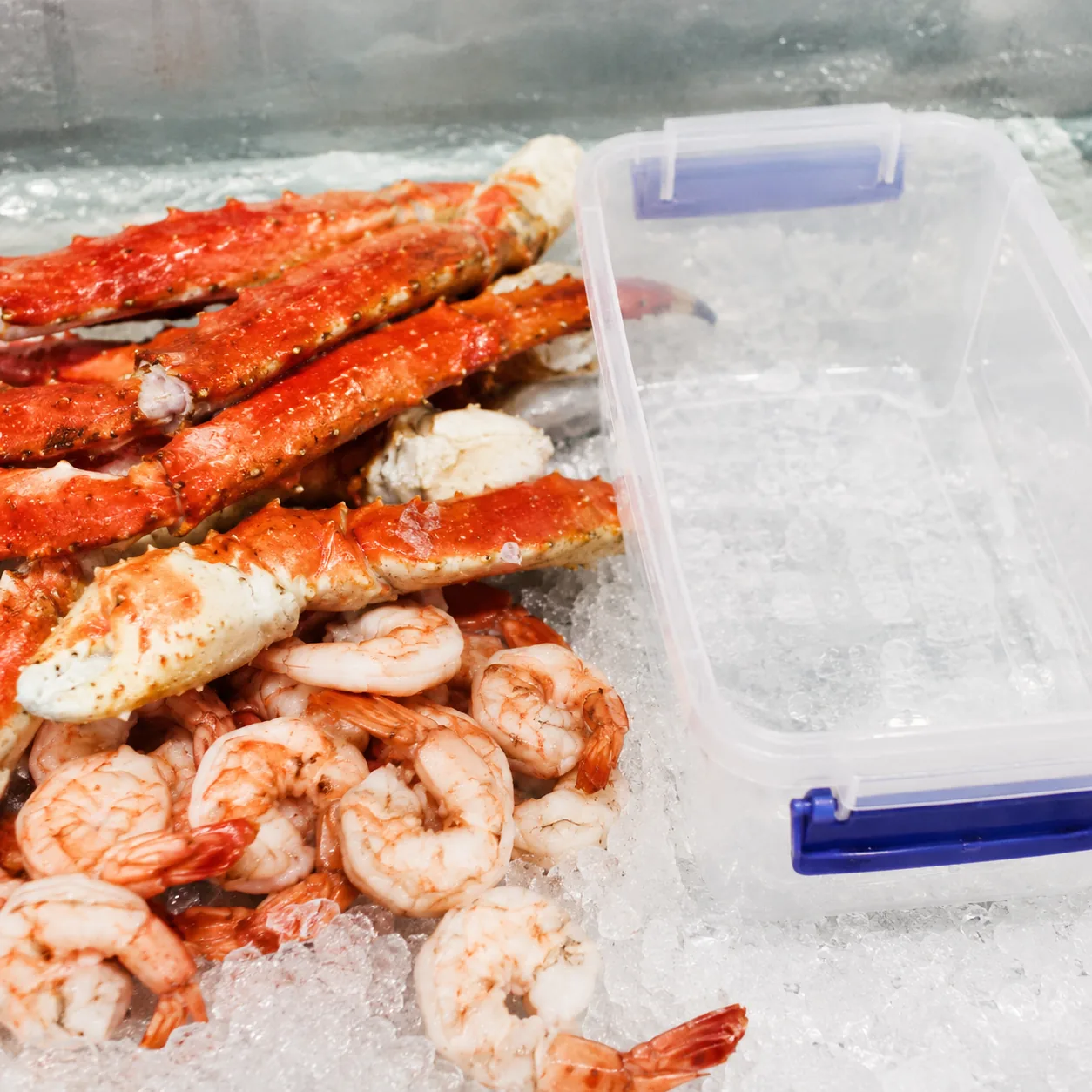 Realistic editorial photo of king crab legs and shrimp on ice beside a freezer-safe container, practical food buying sty