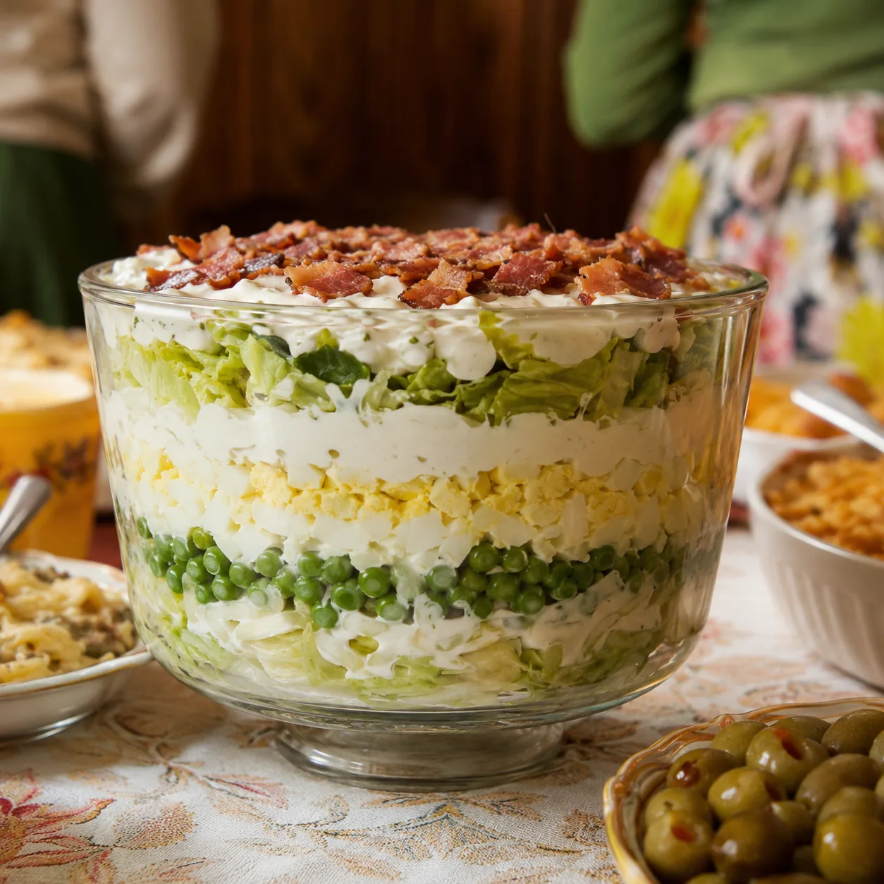 Realistic editorial photo of a seven-layer salad in a glass bowl with peas, lettuce, bacon, eggs, and creamy dressing, p